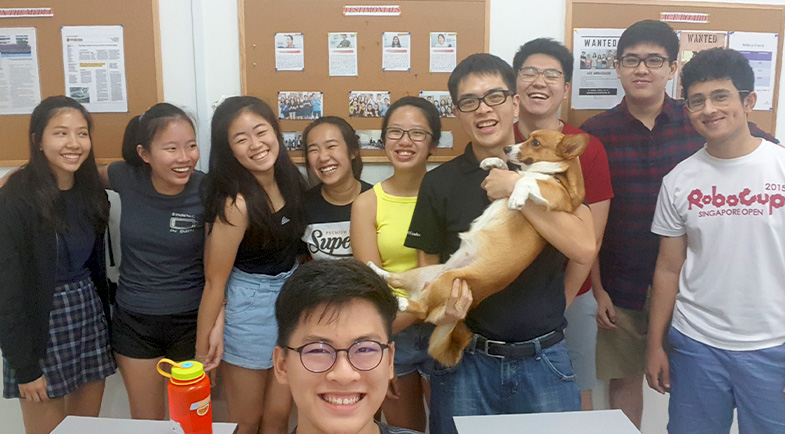 Group of students smiling with a corgi